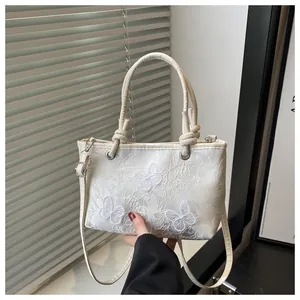 Close-up of exquisite butterfly embroidery on a cream white satin bucket bag for women