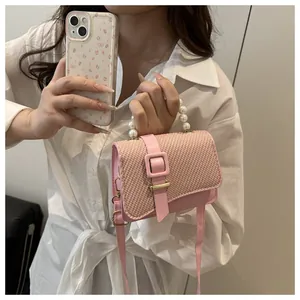 Pink PU crossbody bag featuring woven texture flap with white pearl handle and gold buckle