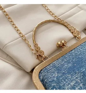 Close-up of blue denim shell bag with ornate golden frame and sunflower engraving