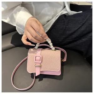 Detail of pink PU mini crossbody bag with pearl handle and woven texture flap on top