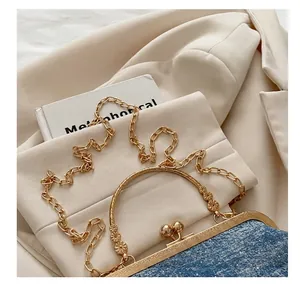 Detailed shot of golden metal round handle and chain strap on blue denim shell bag