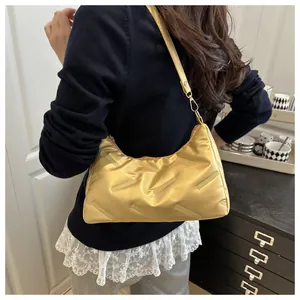 Modella che indossa una borsa hobo trapuntata gialla con finitura metallica e tracolla sottile