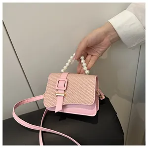 Detail view of pink PU leather handbag with woven flap and elegant pearl handle