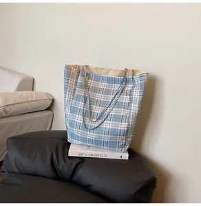 Détail d'un sac cabas en nylon à carreaux bleu et blanc sur un pouf poire noir