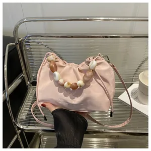 Detalle de bolso rosa plisado con asa decorativa de cuentas de mármol y color ámbar