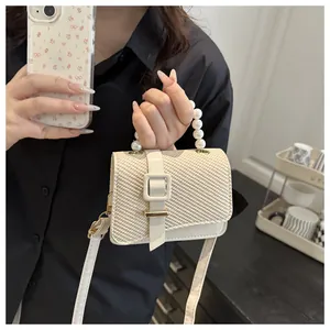 Close-up of off-white woven texture and elegant pearl handle on a mini square bag