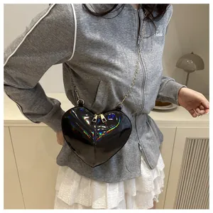 Close-up of black holographic heart crossbody bag with golden chain strap on a model