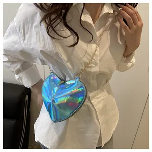 Close-up of holographic heart-shaped crossbody bag with gold chain strap on model