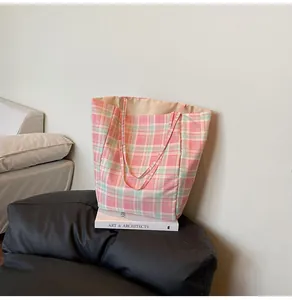 Détail d'un sac cabas en nylon à carreaux rose et vert posé sur un livre de décoration