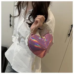 Detail of pink holographic heart-shaped crossbody bag with golden chain strap