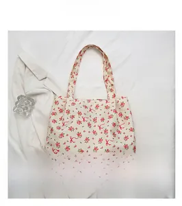 Close-up of floral canvas tote bag with pink roses and red bows on a white blazer