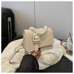 Close-up of pearl handle and woven texture on cream faux leather crossbody bag