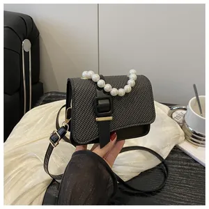 Detailed view of woven texture crossbody bag with pearl handle and metal buckle