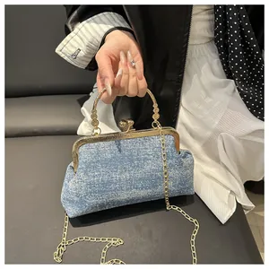 Detail of light blue denim shell bag with vintage gold kiss-lock and metal handle