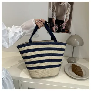 Detail of a striped straw tote bag with bamboo handles on a cozy aesthetic table