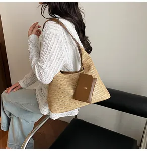 Detail of straw woven crescent tote with a small brown leather pouch and shoulder strap