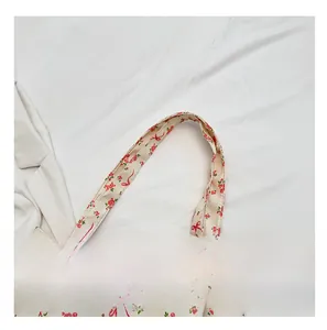 Detail of soft fabric shoulder strap on cream floral tote bag with ribbon print