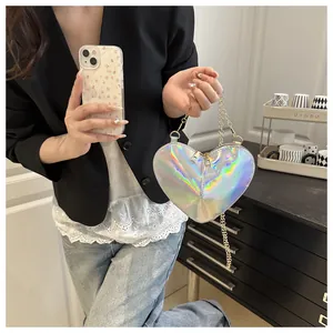 Macro view of holographic heart bag with metallic chain strap held by a model