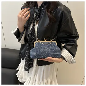 Close-up of small navy denim doctor bag with gold hardware and kiss lock closure