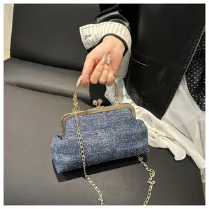 Detail of blue denim shell bag featuring golden metal clasp and chain strap