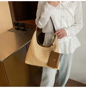 Detail of straw tote bag featuring brown leather straps and attached small coin purse