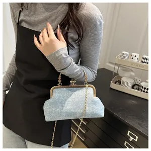 Close-up of blue sequined denim shell bag with gold clasp and chain strap detail