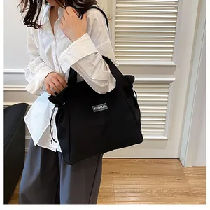 Détail d'un sac cabas en toile noire avec fermeture à cordon et étiquette Fashion devant