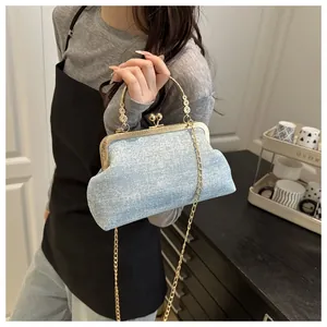Close-up of light blue shell bag with gold hardware and spherical clasp on a model