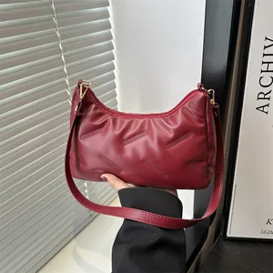Borsa a spalla a mezzaluna rosso scuro con cuciture diagonali e finiture dorate di tendenza