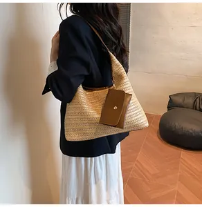 Detail of large woven straw tote bag featuring brown PU leather strap and a matching pouch