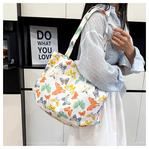Detail of floral canvas tote bag featuring colorful butterfly patterns and a wide strap