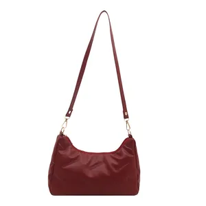 Borsa a spalla a mezzaluna trapuntata rosso scuro con dettagli dorati e zip superiore