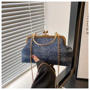 Detail of blue denim shell bag with vintage gold metal frame and heart-shaped lock clasp