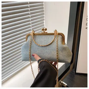 Detail view of light blue denim shell bag featuring shiny rivets and vintage metal clasp
