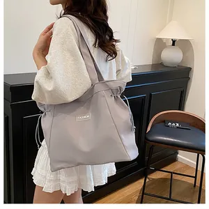 Détail du grand sac cabas gris avec fermeture à cordon et étiquette de mode