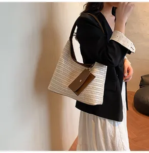 Detail view of woven straw shoulder bag with brown leather trim and detachable small pouch
