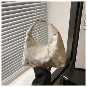 Detail of cream jacquard hobo bag with 3D butterfly floral accents and silver hardware