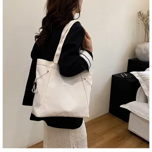 Détail d'un grand sac fourre-tout crème avec étiquette mode et cordons latéraux