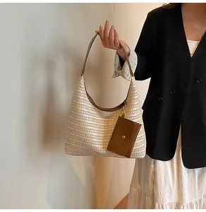 Detail of hand-woven straw tote with brown leather strap and detachable coin purse accessory