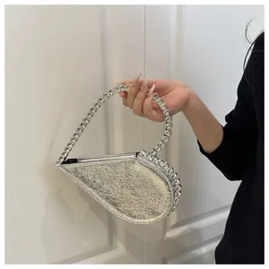 Detail der silbernen herzförmigen Abendtasche mit funkelndem Strassgriff und feiner Textur