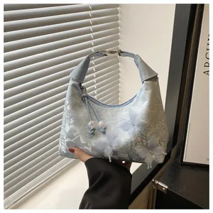 Detail of light blue lace bag featuring 3D butterfly accents and metal buckle strap