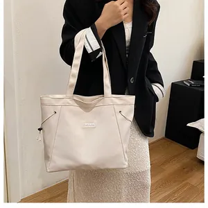 Détail d'un sac cabas en toile avec cordon de serrage et étiquette mode sur tissu écru