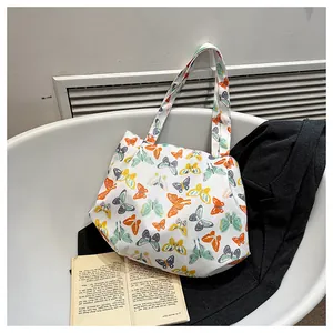 Detail of white floral canvas tote bag featuring colorful butterfly patterns and wide straps