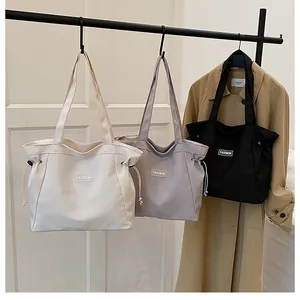 Trois sacs cabas en toile blanc, violet et noir sur un support montrant une grande capacité