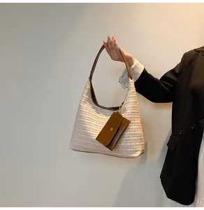 Detailed view of woven straw tote bag texture with brown leather strap and small pouch