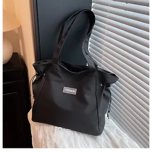 Détail du grand sac cabas en toile noire avec cordon de serrage et étiquette fashion