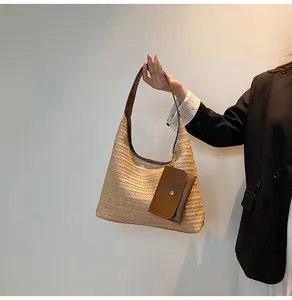 Detail of straw woven tote bag featuring brown leather straps and matching mini pouch