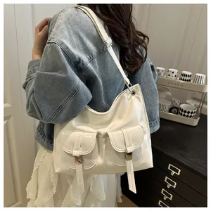 Chic beige glossy tote bag with dual front pockets worn by a model in a modern interior