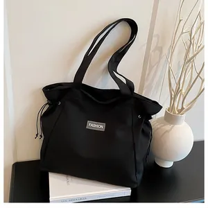 Détail d'un grand sac cabas en toile noire avec cordon de serrage et logo mode