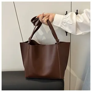 Detailed close-up of a vintage dark brown tote bag in matte faux leather with long straps